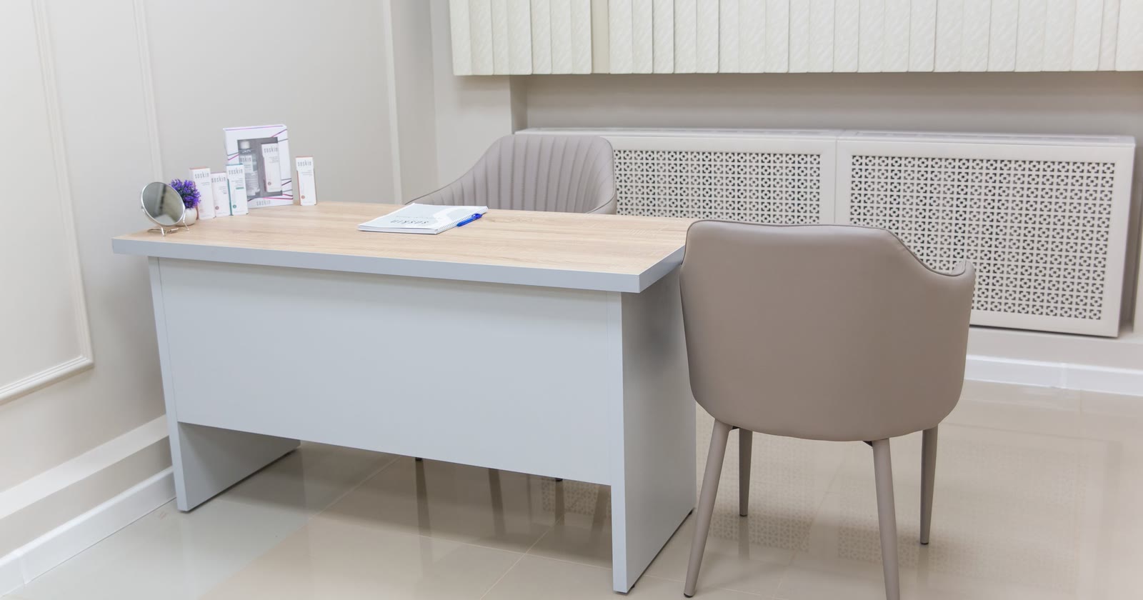 Consultório pequeno e claro, com mesa de atendimento e duas cadeiras